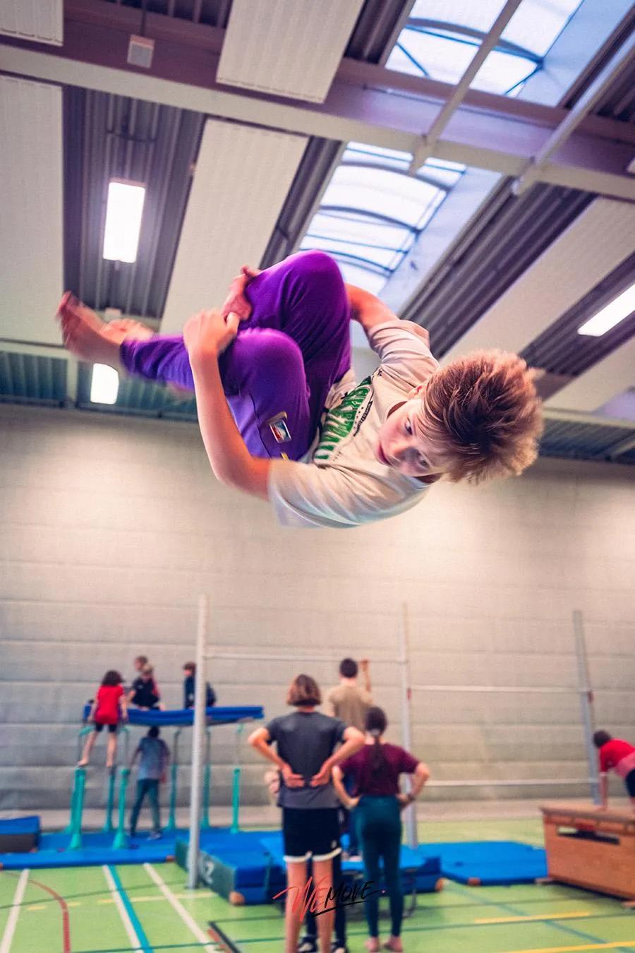 Athlet mitten in der Luft bei einem Salto in der Halle